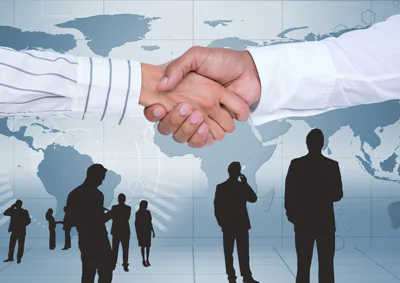 handshake in front of the world map with silhouettes of salespeople