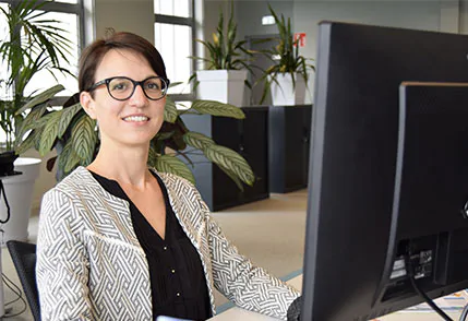 a service client agent smiles behind her computer, go to page Customer Service