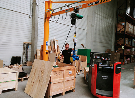 an employee of the warehouse puts a heavy valve in a wooden box using a specific high-picking level handling equipment